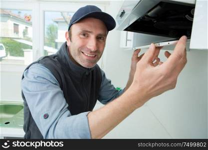portrait of handyman fixing kitchen exhaust