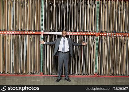 Portrait of happy African American businessman standing arms outstretched in front of thin veneer sheets