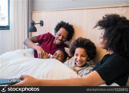 Portrait of happy African American family watching a movie on bed in the bedroom at home. Lifestyle and family concept.