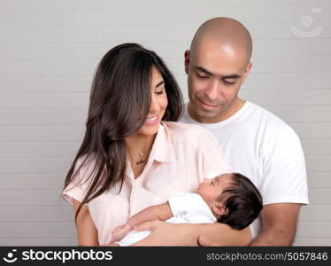 Portrait of happy arabic family at home, young parents holding on hands little sweet newborn baby, love and happiness concept