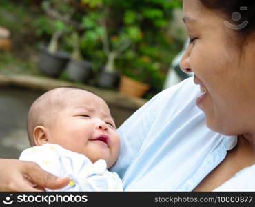 Portrait of happy Asia mother holding his newborn sweet baby dressed. The mommy embracing her baby with love and care. her daughter always happy when she is held.