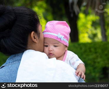 Portrait of happy Asia mother holding his newborn sweet baby dressed. The mommy embracing her baby with love and care. her daughter always happy when she is held.