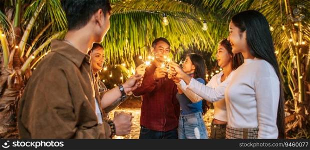Portrait of Happy Asian group of friends having fun with sparklers outdoor - Young people having fun with fireworks at night time  - People, food, drink lifestyle, new year celebration concept.