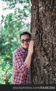 Portrait of Happy Asian man hugging a tree in forest. Protecting and love nature. Environment and ecology concept.