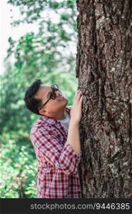 Portrait of Happy Asian man hugging a tree in forest. Protecting and love nature. Environment and ecology concept.