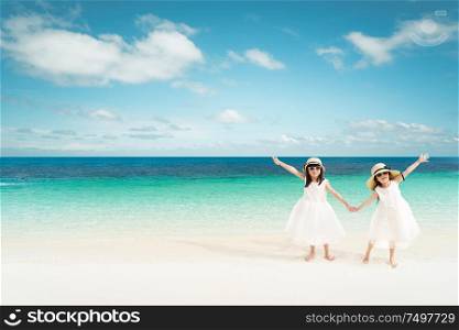 Portrait of happy asian sister at sandy beach in summer vacation .