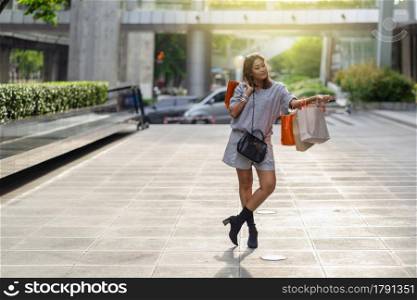 Portrait of Happy Asian woman walking and holding the shopping bag in downtown around shopping center, lifestyle fashion and leisure, sales and black friday concept