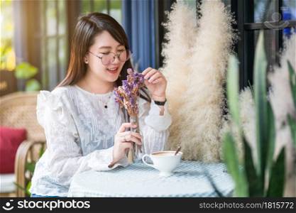 Portrait of Happy Attractive asian people cute woman smelling a purple flowers Bouquet of lavender with coffee cup felt like relaxing in coffee shop like the background