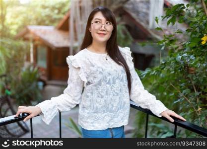 Portrait of Happy Attractive asian people cute woman wearing white lace shirt outside the cafe with shady trees felt like relaxing in house like the background