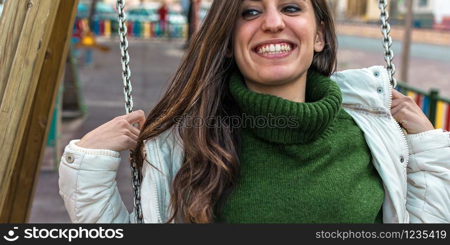 Portrait of Happy attractive hispanic woman playing swinging. hipster style. Cute long hair girl swinging and smiling.. Portrait of Happy attractive hispanic girl playing at a swing set.