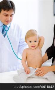 Portrait of happy baby being checked by pediatric doctor using a stethoscope &#xA;