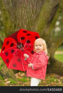 Portrait of happy baby with red umbrella outdoors