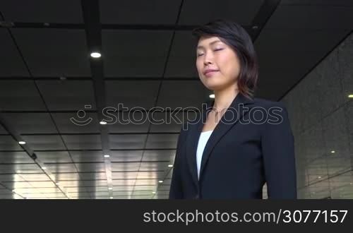 Portrait of happy beautiful Japanese female manager looking at camera. Young Asian businesswoman, confident girl, elegant woman smiling near office building. Career, success. Slow motion