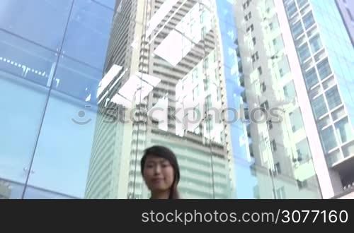 Portrait of happy beautiful Japanese female manager looking at camera. Young Asian businesswoman, confident girl, elegant woman smiling near office buildings. Career, success. Slow motion