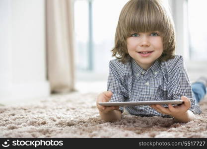 Portrait of happy boy with digital tablet lying on rug at home