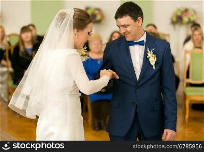 Portrait of happy bride putting ring on groom's finger
