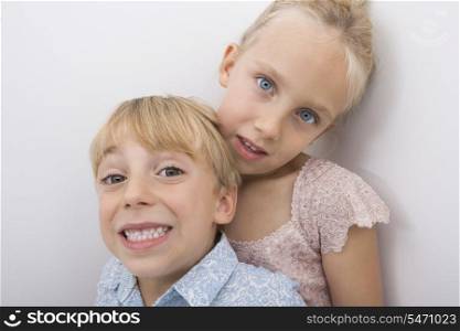 Portrait of happy brother with sister over gray background