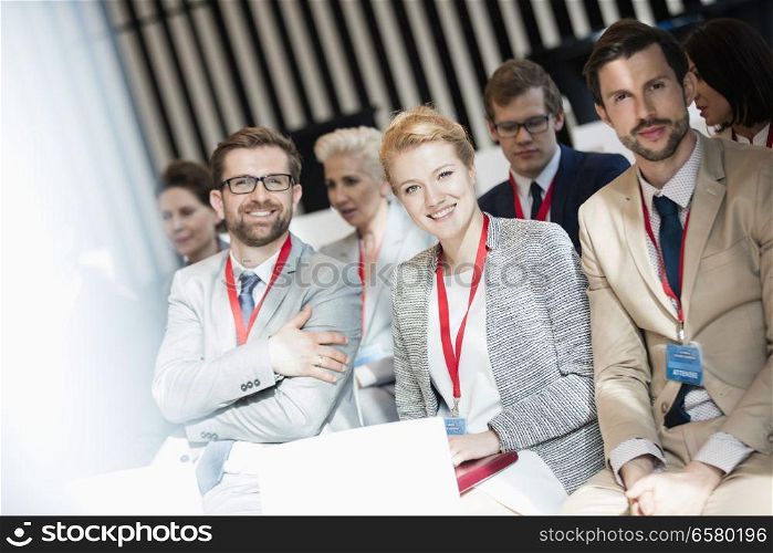 Portrait of happy business people sitting in seminar hall