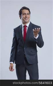 Portrait of happy businessman gesturing against gray background