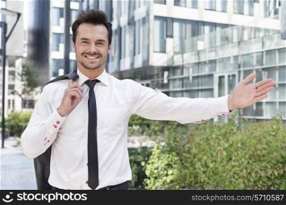 Portrait of happy businessman gesturing while standing outside office building