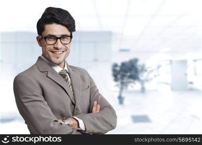 Portrait of happy businessman standing arms crossed in office
