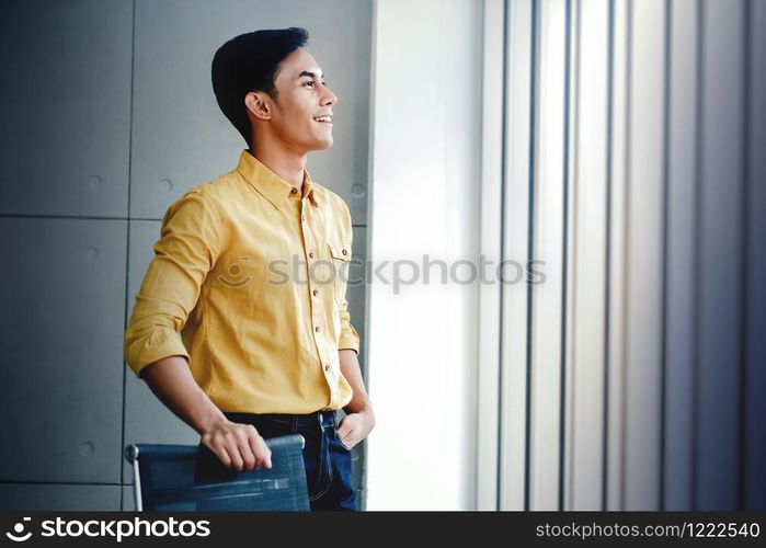 Portrait of Happy Businessman Standing by the Window in Office. Looking Away and Smiling. Dreaming for Success