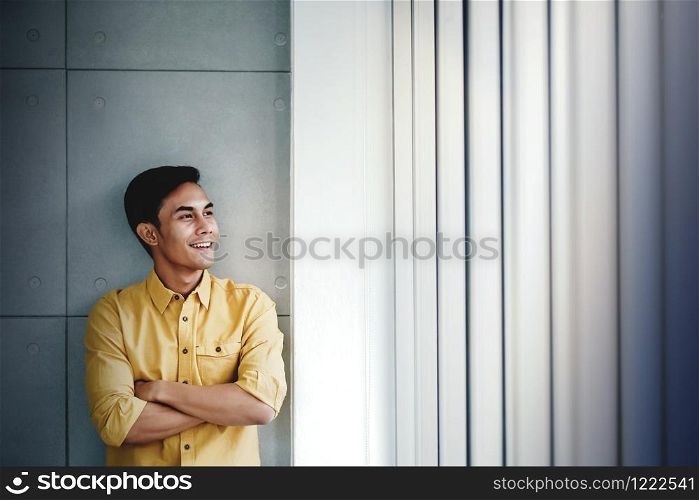 Portrait of Happy Businessman Standing by the Window in Office. Looking Away and Smiling. Dreaming for Success