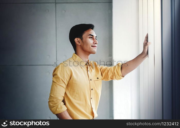 Portrait of Happy Businessman Standing by the Window in Office. Looking Away and Smiling. Dreaming for Success