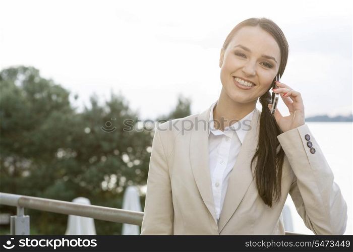 Portrait of happy businesswoman answering cell phone outdoors