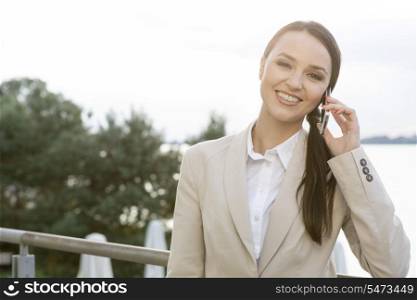 Portrait of happy businesswoman answering cell phone outdoors