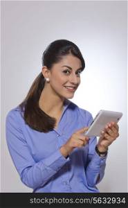 Portrait of happy businesswoman using digital tablet over gray background