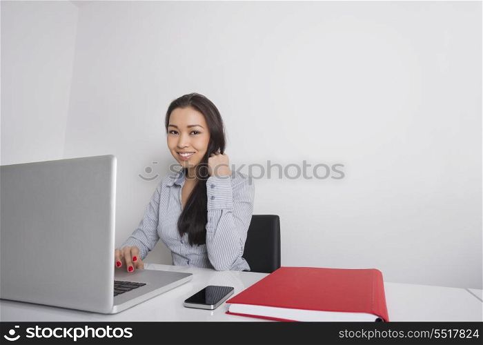 Portrait of happy businesswoman using laptop at office desk
