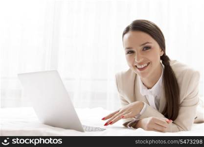 Portrait of happy businesswoman using laptop in hotel room