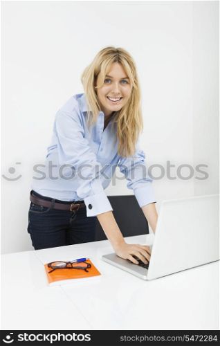 Portrait of happy businesswoman using laptop in office