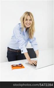 Portrait of happy businesswoman using laptop in office