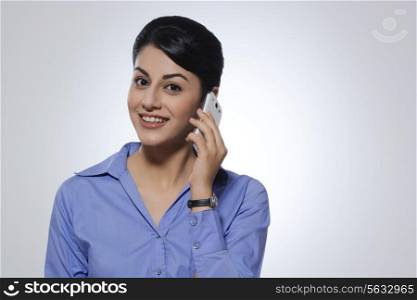 Portrait of happy businesswoman using mobile phone over gray background