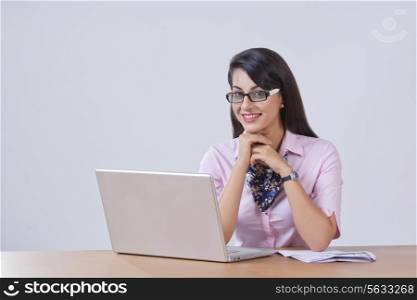 Portrait of happy businesswoman with laptop at office desk