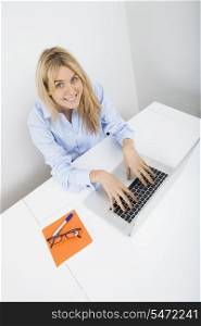 Portrait of happy businesswoman working on laptop in office
