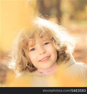 Portrait of happy child against yellow leaves background in autumn park