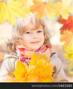 Portrait of happy child in autumn. Frame of golden maple leaves