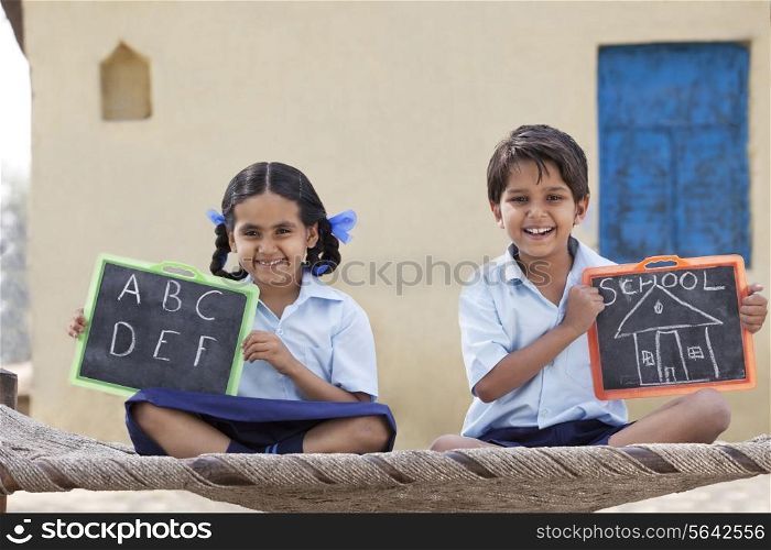 Portrait of happy children in school uniform holding a slate