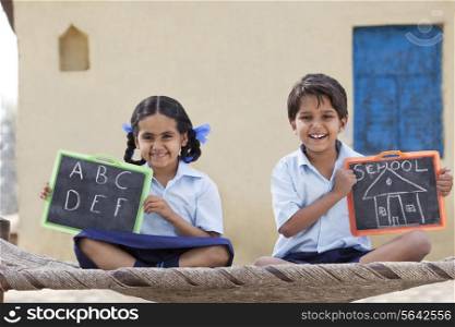 Portrait of happy children in school uniform holding a slate