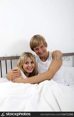 Portrait of happy couple embracing in bed