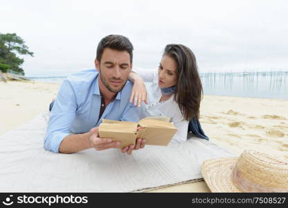 portrait of happy couple reading book on beach