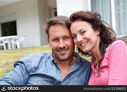 Portrait of happy couple sitting in front of their new house