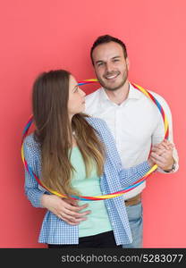 portrait of happy couple with hula hoop isolated on red background