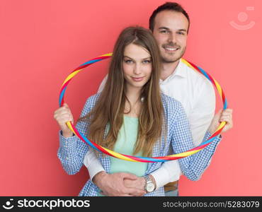 portrait of happy couple with hula hoop isolated on red background