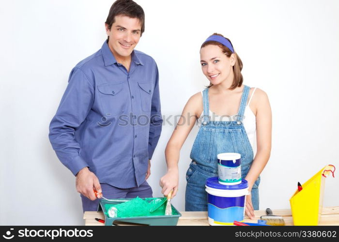 Portrait of happy couple with roller, paint and bucket on table