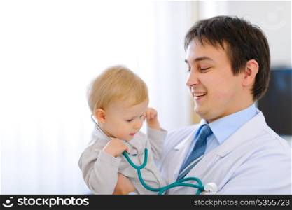 Portrait of happy cute baby with stethoscope on hands of pediatrician&#xA;