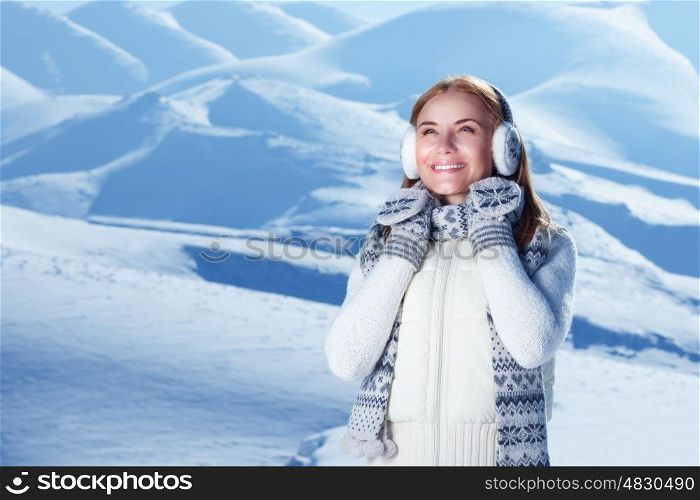 Portrait of happy cute woman standing outdoors and wearing beautiful warm knitted set, spending winter holidays in the snowy mountains